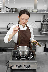 年轻女性糕点厨师在沸腾的糖浆上加了活塞糊 在专业厨房做甜点图片