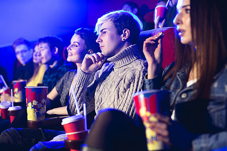 朋友们坐在一起吃爆米花 同时在电影院看电影观众女朋友友谊夫妻成人女士复用剧院女孩男人图片