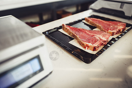 在一家屠夫店里把生肉塞进盘子里奶牛产品包装餐厅牛扒猪肉切菜板鱼片黑色盒子图片