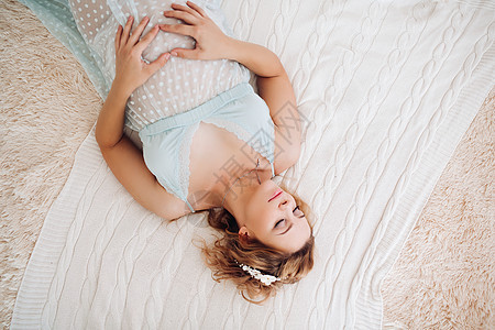 金发孕妇躺在床上用手触摸肚子的肚皮卧室怀孕睡衣婴儿妈妈金发女郎女性内衣身体产妇图片