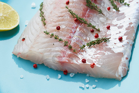 白底蓝盘上的原白色长眼鱼小片 一整块鲜鱼烹饪产品桌子美味食物草本植物栖息美食家盘子石头图片