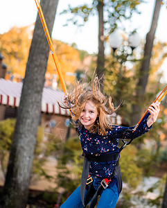 微笑的小女孩跳到蹦床上绳上高度活动绳索乐趣城市操场幸福娱乐公园童年图片