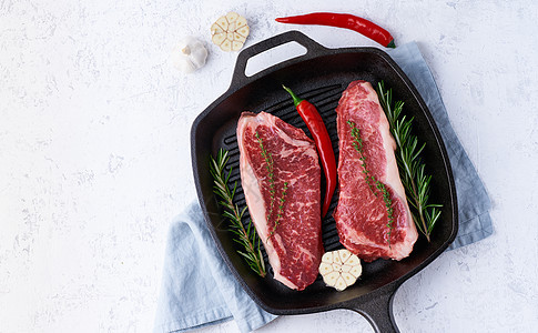 两块新鲜的生肉 牛肉片 大理石条形板 放在铸铁大锅里图片