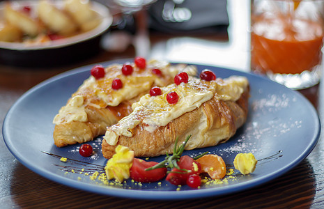 新鲜出炉的羊角面包 配上白色 柔软 甜美的奶油 盘子里放着红色浆果 在餐厅的深色木桌上享用欧陆式早餐 包括两个美味的羊角面包和奶图片