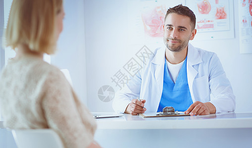 英俊的医生正与年轻的女病人交谈 在办公室做笔记 在办公室里作笔记药品帮助塑料成人考试治疗化妆师诊所男人诊断图片