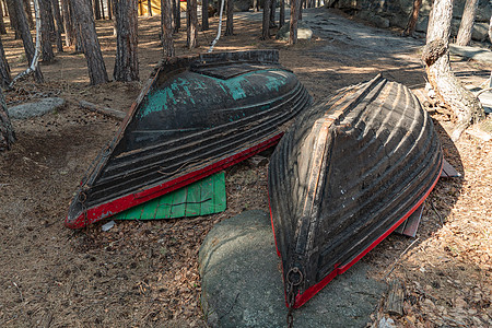 林间山湖码头岸边 停泊着两艘破旧的渔船 在沿海地带或海岸上翻倒的木船 海岸线土地林业码头树木独木舟帆船船运港口游艇海湾图片