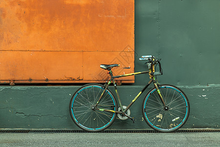 一辆自行车在钢橙门前 有绿墙的仓库人行道橙子入口建筑学旅行运输金属绿化车轮潮人图片