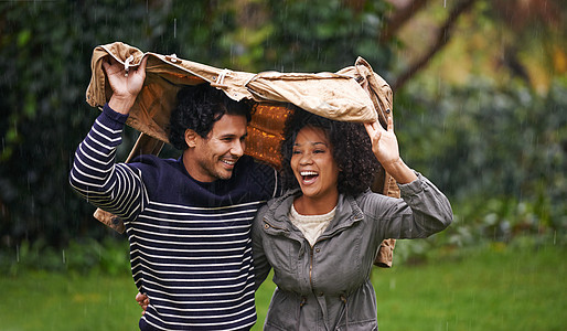 快 到我的夹克下面来 拍到一对情侣为了躲避雨而爱护的年轻夫妇图片