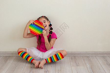 坐在地板上 靠着一堵轻墙 握着彩虹在她手里弹出图片