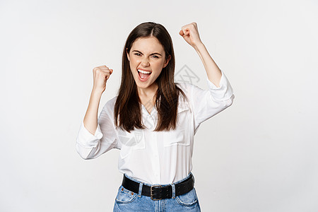 兴奋的年轻成年女性对胜利做出反应 惊喜消息 尖叫和欢呼 胜利 实现目标和庆祝 站在白色背景上商业学生职业商务工作工作室广告黑发售图片
