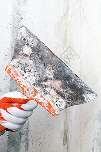 在灰水泥墙背景上 粉刷师手手里拿着一把旧式特别刮刀图片