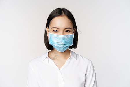 Covid 和医疗保健概念 亚洲女性的特写肖像 戴着面罩的办公室女士 微笑着 在大流行期间使用冠状病毒保护措施 白色背景面具女孩图片