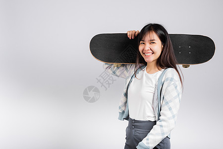 欢笑的快乐女人 肩上坐着滑板工作室微笑女孩滑冰溜冰者运动乐趣青少年长板木板图片