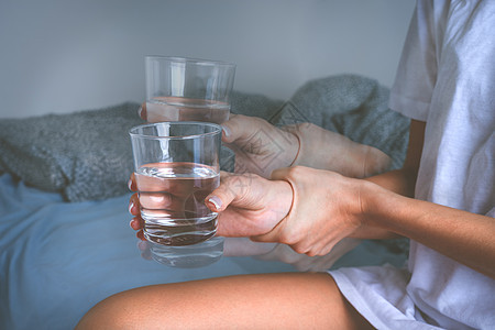 女人手握着杯子的水 患上帕金森病症或基本震颤的痛楚图片