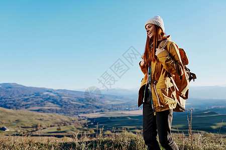 身穿黄色夹克 头戴帽子背包的女旅行者在山区旅行山路环境爬坡岩石顶峰女性滑雪自由女士旅游图片