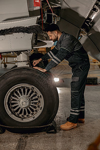 在机库修理飞机轮的男机械技工图片