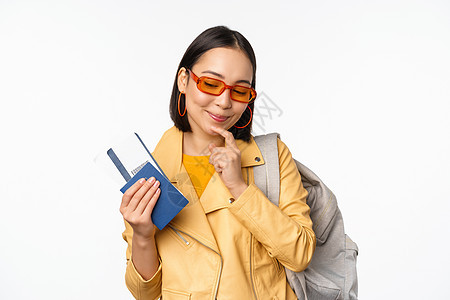 带登机票和护照到国外旅游的亚洲女游客 持有背包 考虑旅行 站在白背景上站立以及情感门票微笑工作室成人女孩商业促销解决方案黑发图片