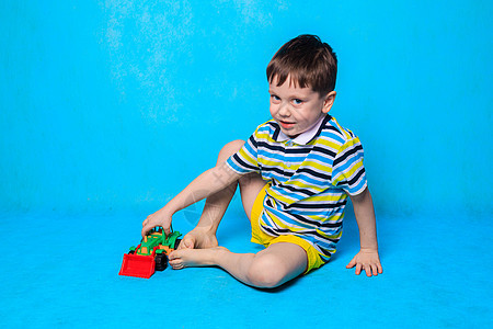 一个男孩正在蓝色背景上打打字机 一篇关于儿童休闲的文章 儿童游戏 儿童车孩子车轮运输活动运动机器婴儿玩具安全汽车背景图片