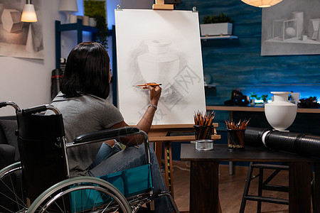 坐在轮椅上画艺术花瓶彩礼的年轻插图员图片