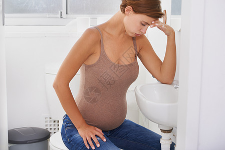 一个孕妇在浴室里 忍受着早晨的病痛 - 她正在洗手间中挣扎图片