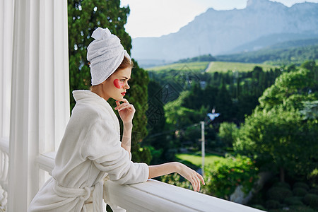 身穿白袍的肖像女人 在阳台上俯视着未改变的山岳酒店咖啡杯子治疗身体女性奢华眼睛毛巾浴衣图片