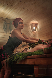 一名妇女在扫帚的帮助下为一名男子举行沐浴仪式 一个人躺在云杉树枝上澡堂女性治疗蒸汽温泉桑拿疗法皮肤蜡烛两个人图片