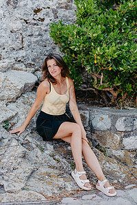 美丽的女孩坐在布德瓦老城的石墙上 女孩坐在石栏杆上 布德瓦 黑山天空旅行女性景观堡垒裙子岩石游客蓝色旅游背景图片