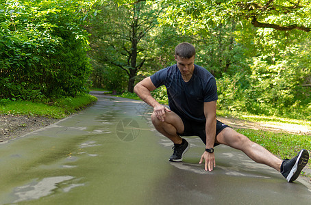 一位年轻的耐力运动员正在户外的森林里做伸展运动 在森林周围 橡树周围 跑步者自然 健身慢跑运动员慢跑 森林人 秋跑 双脚舒展图片