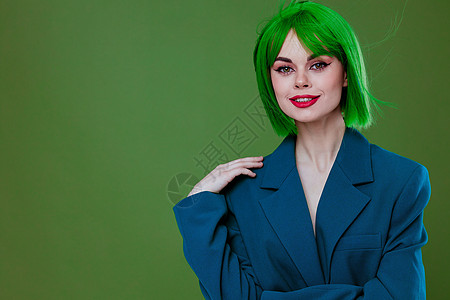 身着绿色假发蓝色夹克的正阳性年轻女子 未改变绿背景衣服购物时尚情绪情感女孩魅力展示成人紫色图片