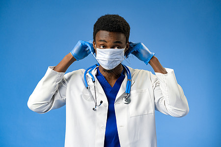 蓝色工作室的面罩和手套上的自信黑人医生爆炸风险男人奉献外套手术药品医师外科工人图片