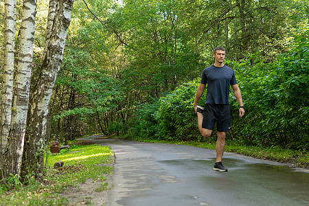一名男子运动员在户外的公园里跑步 在森林周围 橡树绿草年轻持久的运动员跑步者慢跑者耐力休闲男性 在外面 秋身横 脚伸图片