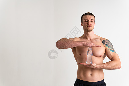 男性饮水健身是用一条毛巾抽在白色背景上孤立的健康身体 水上运动成年男子 背景有氧运动 力量蛋白质完美 累了一块肌肉图片