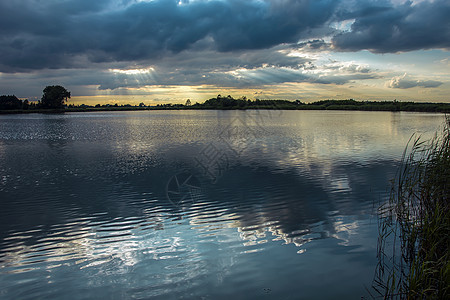 宁静的湖面上云彩中的阳光图片