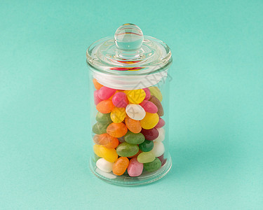 装有糖的玻璃罐子 绿宝石背景上的糖果图片