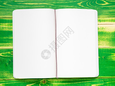 张开笔记本 有两个白色白页 躺在明亮的绿色木制桌子上 模型图片