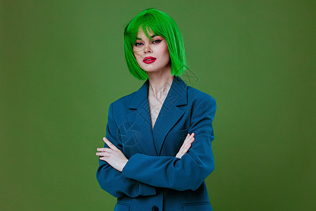 一位身穿绿色假发蓝色夹克 绿色背景不变的迷人女士的肖像购物魅力潮人夏装紫色衣服成人销售配件帽子图片