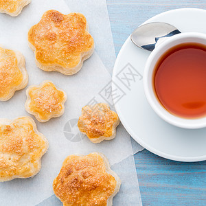 传统早餐 包括一杯茶和甜糕点 — 烤饼 一杯茶 勺子 在木制蓝色桌子上 俯视图片
