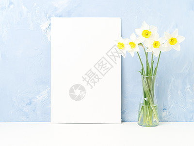 鲜花 白桌上的空白纸 正对蓝色纹质混凝土瓦图片