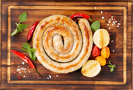 香肠 螺旋形 蔬菜洋葱 胡椒和西红柿在黑木切削板上 顶视角图片