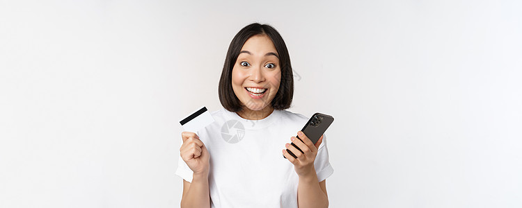 网上购物 快乐的亚洲女性使用信用卡和智能手机应用程序 通过手机在网站上付款 白色背景女朋友成人细胞女孩互联网工作室学生横幅银行业背景图片