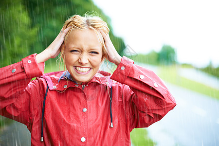 没有什么比一点新鲜的雨水更好的了 美丽的年轻金发女人在乡间小路上的户外雨中穿着一件红色雨衣图片