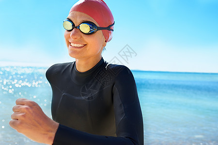 一名年轻女子在冬天的海滩上 接受全副身穿湿衣和游泳装备的培训 笑声 掌声跑步女性训练蓝色微笑成人海洋运动风镜天空图片