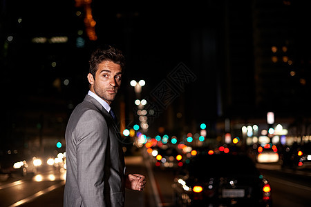 一个英俊的商务人士在夜里穿过繁忙的城市街道 过夜时穿梭于城市图片