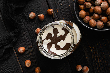 巧克力撒布或甜甜奶油加栗子 在黑色木制桌底的黑木板背景上 顶层视野平面图片