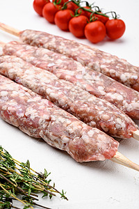 在白石桌背景上 配有烧烤成分的羊肉烤肉串和制成的羊肉面条图片