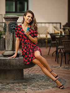 年轻快乐的女子 穿着黑礼服 红鲜花 在街上咖啡厅附近吃美味冰淇淋图片
