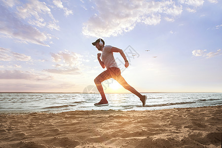 运动男子在日落时在沙滩上奔跑图片
