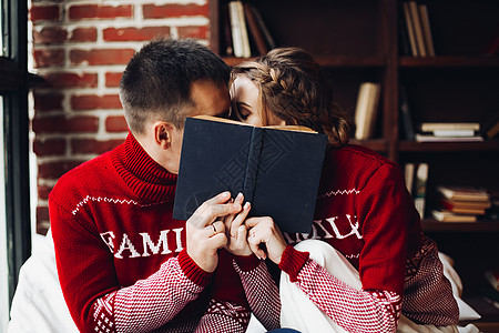 爱情侣在冬季跳跃者亲吻 在书后隐藏背景图片