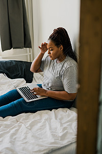 非洲裔美国年轻女性在床上使用笔记本电脑  技术 通信和社交网络概念说谎电子邮件微笑毯子阅读幸福成人闲暇互联网卧室图片