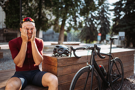 精疲力尽的人骑完自行车后在休息时碰面时抚摸脸部图片